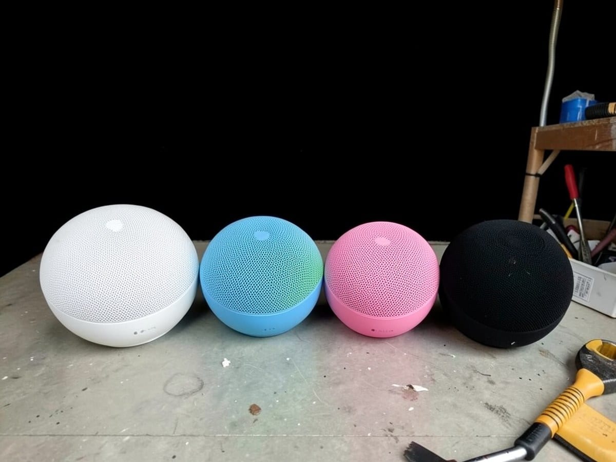 Five Apple HomePod speakers in various colors (white, blue, green, pink, black) are arranged in a semi-circle against a black background.