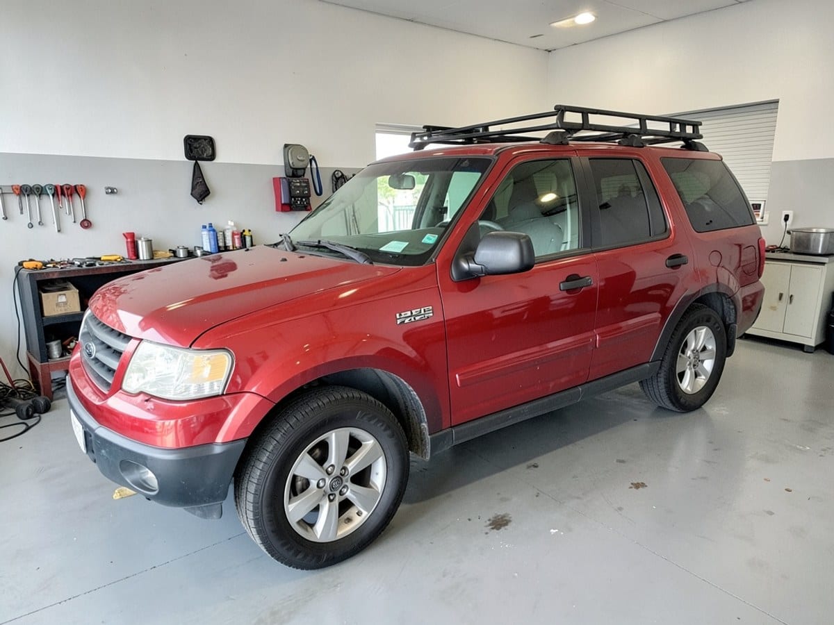 red 1998 Ford Explorer SUV with black roof rack and silver wheels is parked in a bright showroom with a gray floor and white walls.