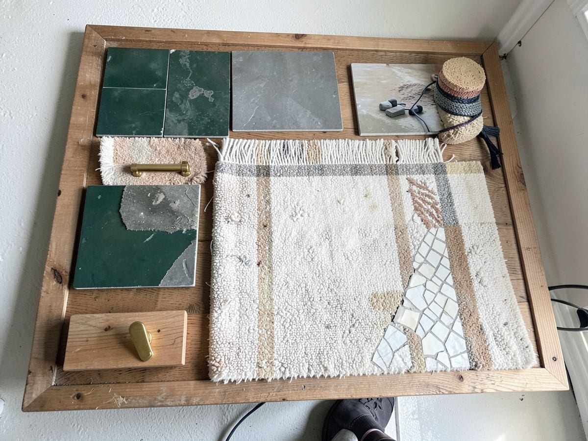wooden board displays a diverse array of objects, including green and gray tiles, a white and beige rug, a gold handle, a wooden block, and a white and beige mosaic.